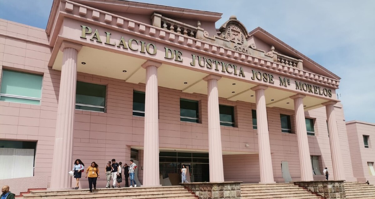 Vista exterior del edificio color rosa del Palacio de Justicia José María Morelos en Michoacán con personas caminando en los escalones