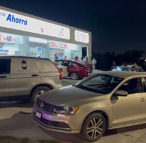 Se observa una fachada con el letrero de Farmacia del Ahorro y unos policías afuera del lugar.