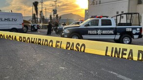 Cinta amarilla de prohibido el paso al lado de una patrulla de policía