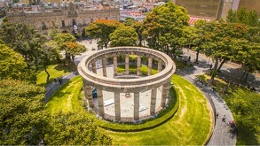 Una vista aérea del Monumento de la Rotonda de los Jaliscienses Ilustres en Guadalajara. Es un monumento circular de cantera con columnas al aire libre, rodeado