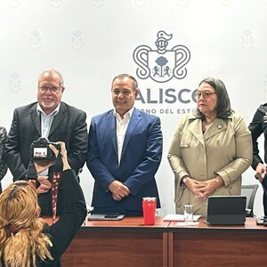 Funcionarios de seguridad en Jalisco siendo fotografiados de pie delante de una mesa ante los medios de comunicación en conferencia de prensa