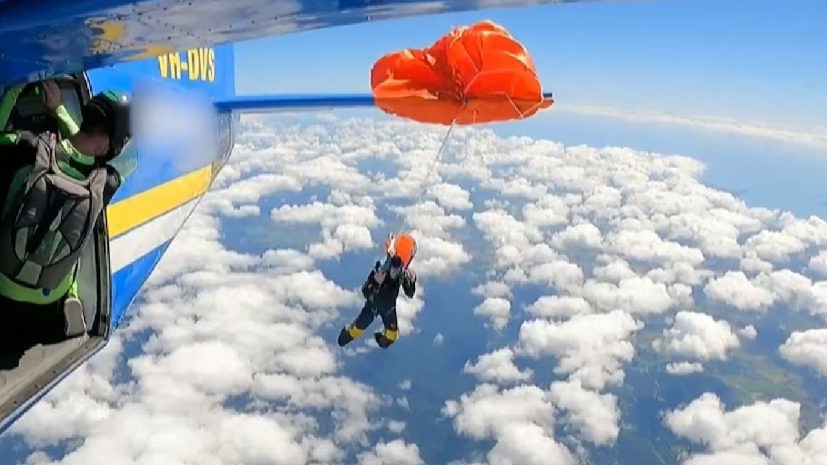 Paracaidista en cola de avión en cielo azul y blanco
