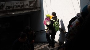 Joven bajando al metro con un ramo de flores.