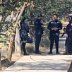 Oficiales de la Policía Municipal de Guadalajara parados sobre la banqueta en el área acordonada con árboles alrededor