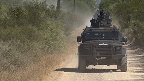 Se ve una camioneta color  negra, en medio de una terracería.