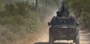 Se ve una camioneta color  negra, en medio de una terracería.