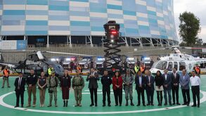 Personas formadas afuera del estadio Cuauhtémoc de Puebla con helicópteros y patrullas al fondo.