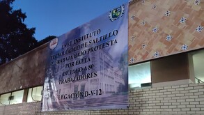 En la imagen se observa una lona blanca con un texto pegada sobre un edificio.