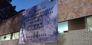 En la imagen se observa una lona blanca con un texto pegada sobre un edificio.