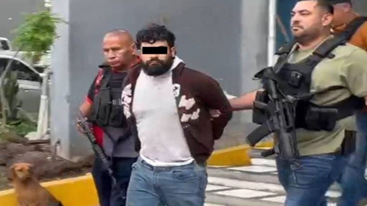 Dos personas armadas llevando detenido a un hombre.