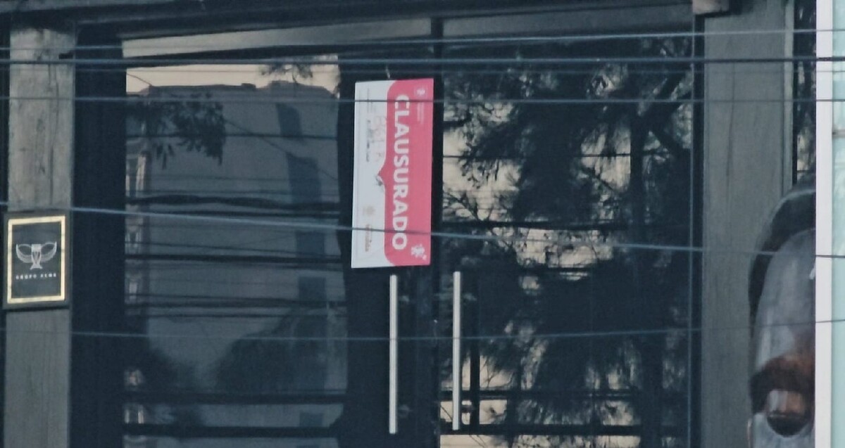 Letrero oficial de clausura colocado sobre una de las puertas de vidrio del antro Strana tras el incendio