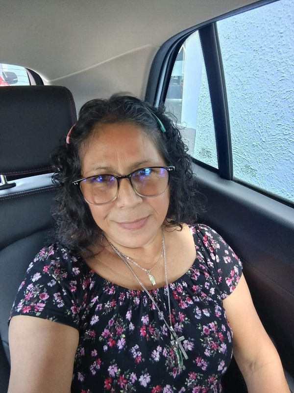 Una mujer de edad avanzada posando para una fotografía desde su vehículo.