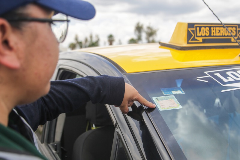 Un policía señalando una calcomanía pegada en un taxi en Puebla.