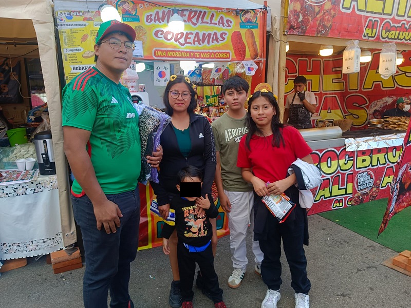 Una familia posando para la cámara frente a un puesto ambulante de comida.
