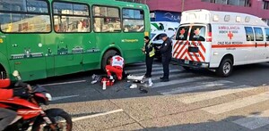 Paramédicos de la Cruz Roja de Guadalajara atendiendo a una mujer tendida en el pavimento a un costado del camión verde de la ruta 175A y una moto pasando