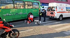 Paramédicos de la Cruz Roja de Guadalajara atendiendo a una mujer tendida en el pavimento a un costado del camión verde de la ruta 175A y una moto pasando