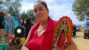 Una mujer sosteniendo una imagen de la Virgen de Guadalupe en Puebla.