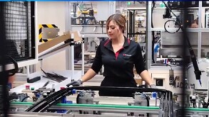 Se observa una mujer que está con unas máquinas, trae un pantalón y camisa negra.