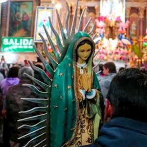 Figura de la Virgen de Guadalupe siendo sostenida por un hombre visto de espaldas, dentro del Santuario de la Virgen de Guadalupe en Guadalajara