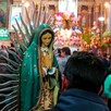 Figura de la Virgen de Guadalupe siendo sostenida por un hombre visto de espaldas, dentro del Santuario de la Virgen de Guadalupe en Guadalajara