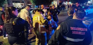 Bomberos y paramédicos de Morelia atendiendo a mujeres heridas con policías y personas alrededor en medio de la calle