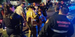 Bomberos y paramédicos de Morelia atendiendo a mujeres heridas con policías y personas alrededor en medio de la calle