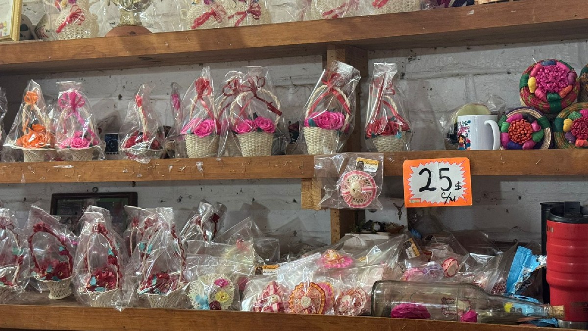 Dos mujeres de mediana edad en el interior de una tienda de dulces y artesanías. Una clienta mira los productos mientras la vendedora