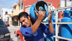 un hombre carga un tanque de gas lp para entregar en una casa en puebla