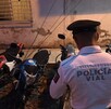 Un oficial de Policía Vial (uniforme blanco y gorra oscura) está de espaldas, de pie entre varias motocicletas de diferentes colores (rojo, blanco y azul)