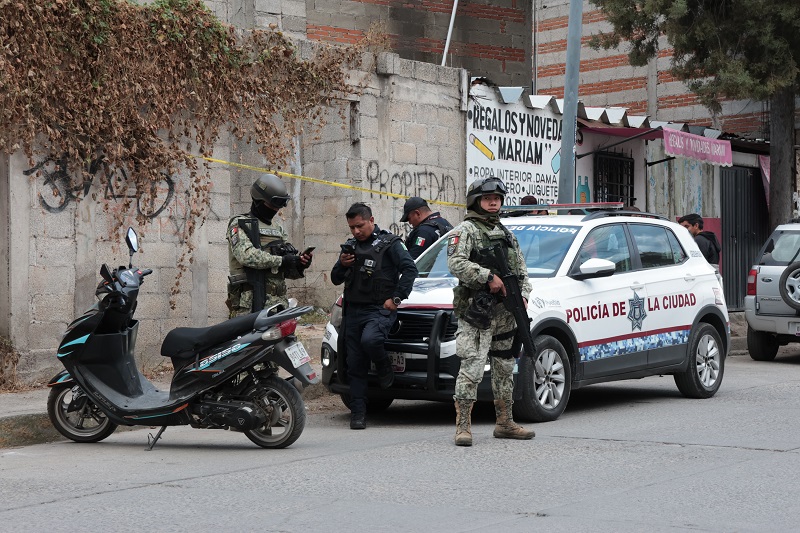 Policías y militares resguardando una zona acordonada tras ocurrir un crimen.