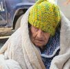 Una mujer de la tercera edad cubierta con un gorro y en silla de ruedas.