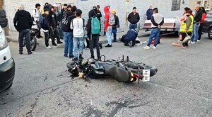 Motocicleta volcada sobre la vía pública en Tlaquepaque con una multitud de personas detrás y otros vehículos estacionados alrededor
