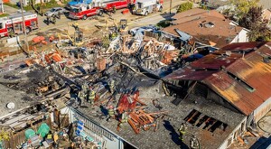 Vista aérea de escombros y pedazos de una casa calcinados tras explosión en California con bomberos trabajando alrededor