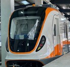 Una vista de primer plano de un tren moderno con detalles anaranjados y blancos, estacionado dentro de una estación cubierta. Este tren es para la Línea 4