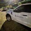 Camioneta del Instituto Jalisciense de Ciencias Forenses estacionada detrás de diversos automóviles y al lado de un camión verde durante la noche