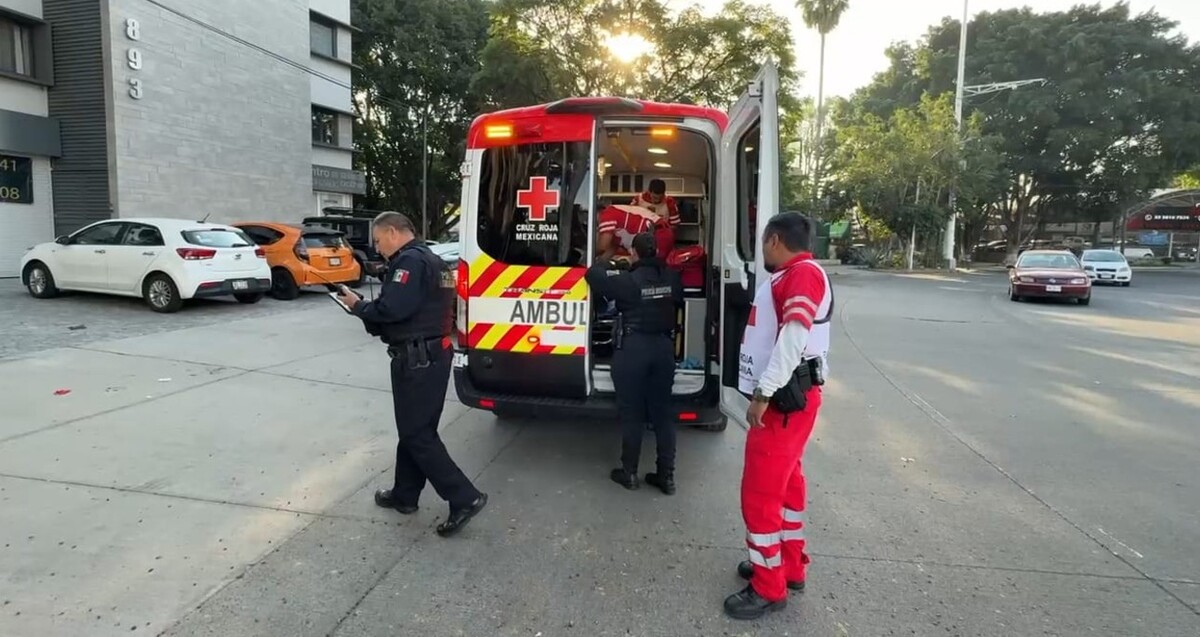 Paramédicos de la Cruz Roja dentro de una ambulancia brindado atención a hombre herido con oficiales de la Policía de Guadalajara presentes