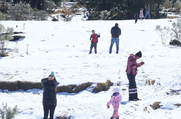 Se observa nieve y personas con chamarras, entre ellos mujeres y niños.