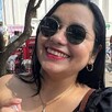 Mujer con piel morena clara con lentes oscuros y sonriendo
