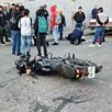 Motocicleta volcada sobre la vía pública en Tlaquepaque con una multitud de personas detrás y otros vehículos estacionados alrededor