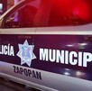 Vista lateral de una patrulla de la Policía Municipal de Zapopan estacionada en la calle de noche y con la sirena encendida