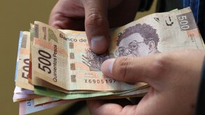 Un hombre contando billetes mexicanos con la mano.
