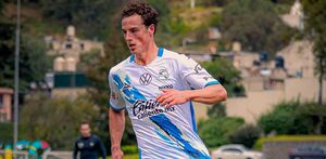Un hombre delgado jugando un partido de futbol vistiendo una playera del Club Puebla.