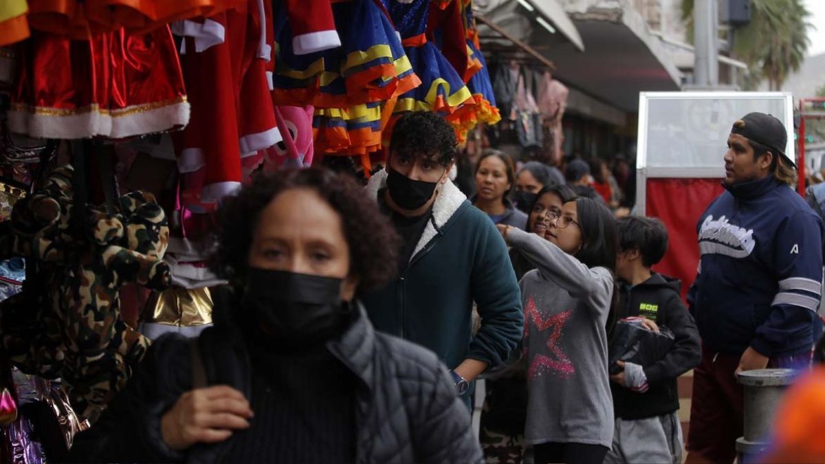 Personas con cubrebocas y gorros de Navidad caminando en las calles de Torreón.