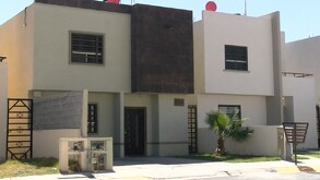 Se ve una casa color beige con fachada  color café, y una palma color verde.