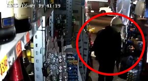 Hombre encapuchado y con la cara cubierta dentro de una tienda de abarrotes en Guadalajara. Un circulo rojo resaltando la silueta del hombre