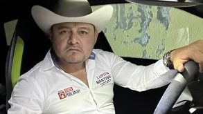 Hombre con sombrero y camisa blanca al interior de un auto de lujo.