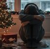 hombre depremido sentado junto a su árbol navideño