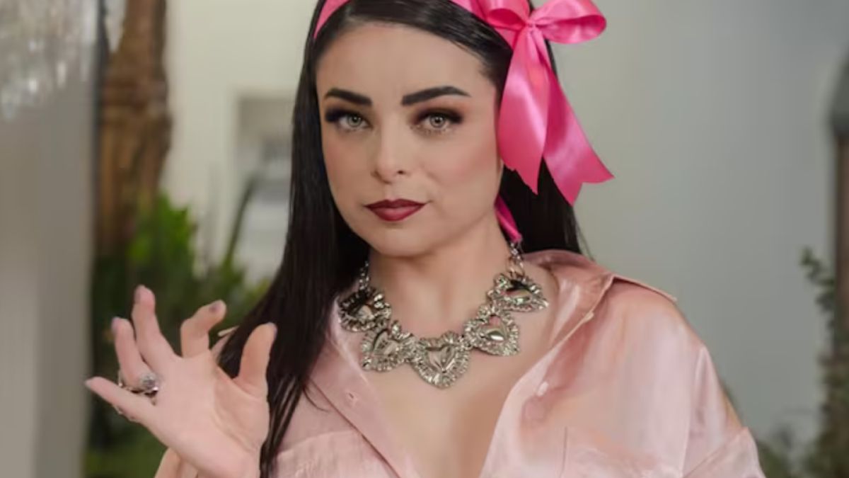 Violeta Isfel con una blusa color rosa palo y un listón en la cabeza color rosa fiusha