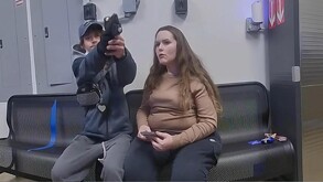 Hombre apuntando con un arma a un policía.