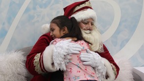 Un hombre disfrazado de Santa Claus abrazando a una niña.